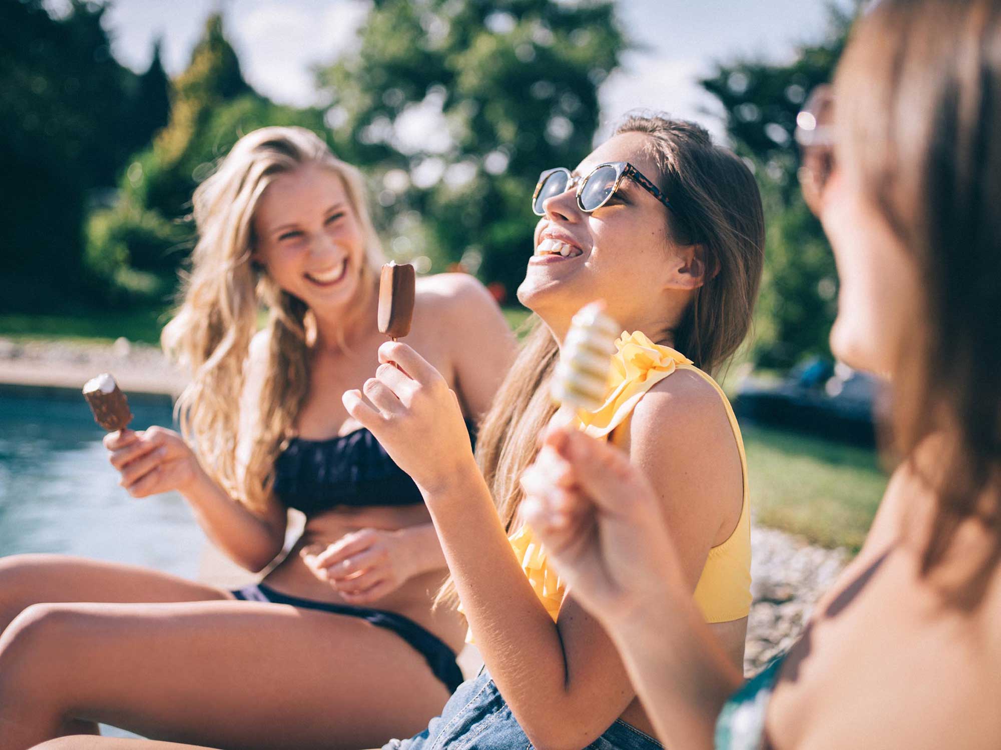 Women eating ice cream and laughing by the pool