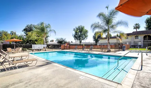 Shadow Mountain Apartments community pool lounge area showing pool chairs and entrance to building and palm trees in the background